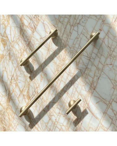 Tirador de mueble en latón modelo 04 diseño sobre una superficie de mármol acompañado de largas manillas alineadas