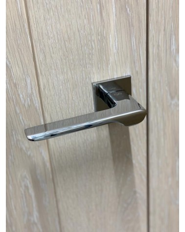 Tirador de puerta cromo pulido LIGNE diseño vista superior inclinada montada en una puerta