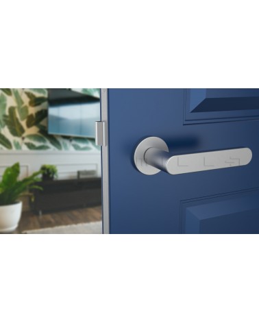 Manija de puerta cromo satinado ALORA manija de diseño vista frontal montada en una puerta entreabierta
