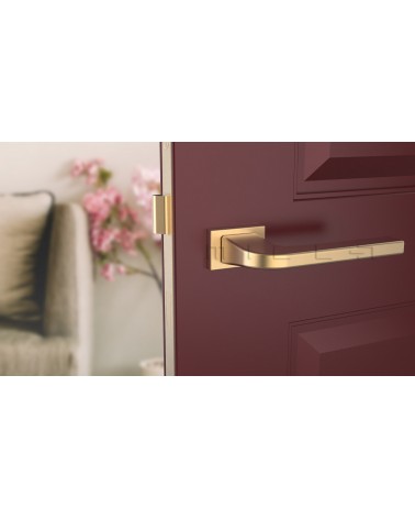 Manija de puerta oro mate ISMENA ferretería diseño vista frontal montada en una puerta