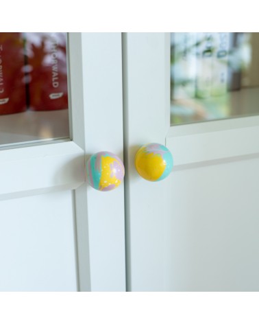 Botón de mueble de madera de haya amarillo funky, tirador de diseño en vista inclinada montado en una puerta semiacristalada