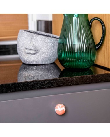 Botón de mueble en madera de haya rojo cereza tirador de diseño fijado en una fachada de mueble gris bajo una encimera