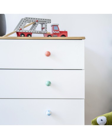 Botón de mueble en madera de haya rojo cereza tirador de diseño instalado en una cómoda blanca