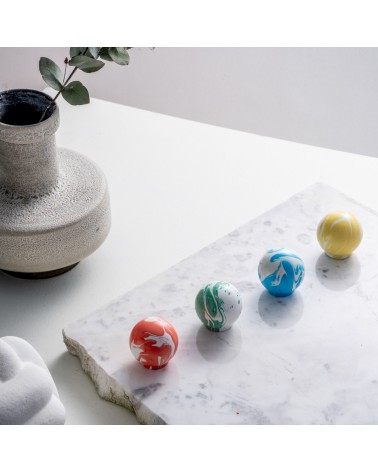 Botón de mueble en madera de haya rojo cereza tirador de diseño posados sobre una superficie de mármol blanco