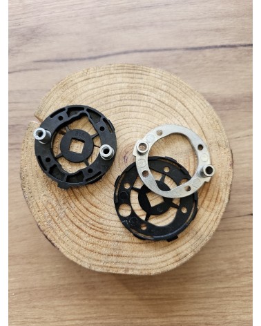 Dos adaptadores de montaje rápido para tiradores de puerta vistos de atrás, apoyados sobre una mesa de madera