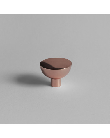 Botón de mueble de cobre LUNA M tirador de diseño visto de frente colocado sobre una superficie gris
