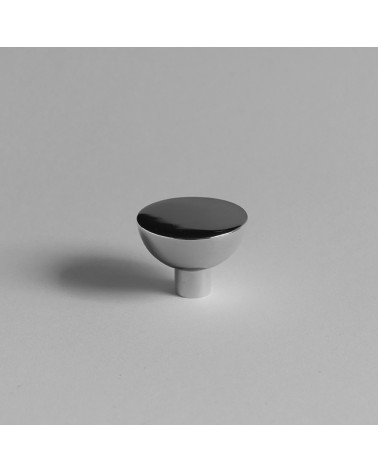 Botón de mueble cromo pulido LUNA M colocado sobre una superficie gris