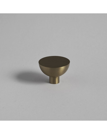 Botón de mueble dorado mate LUNA M tirador de diseño colocado sobre una superficie plana con fondo uniforme