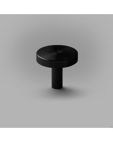 Botón de mueble negro NENA M tirador de diseño colocado sobre una superficie plana