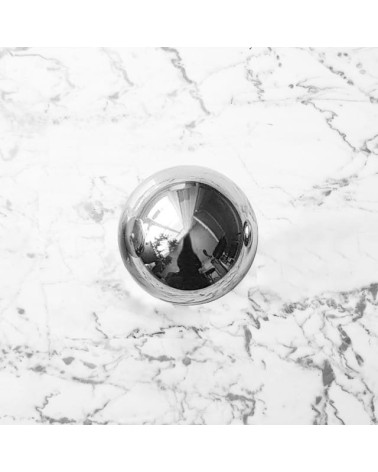 Botón de mueble cromo pulido ODETE M tirador de diseño colocado sobre una superficie marmolada