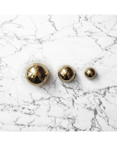 Botón de mueble oro pulido ODETE tirador de diseño colocado sobre un fondo de mármol