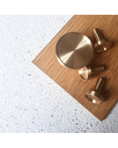 Botón de mueble en latón INA tirador de diseño vista desde arriba posado sobre una placa de madera
