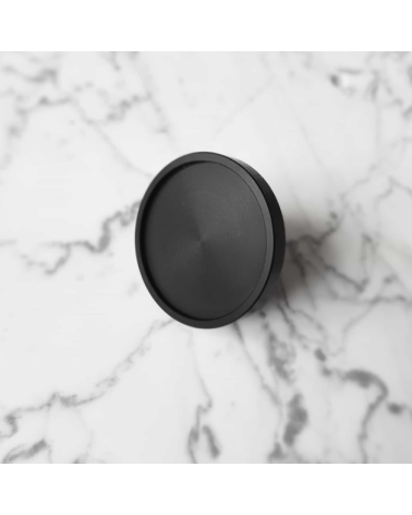 Botón de mueble negro INA BLACK tirador de diseño modelo grande posado sobre una superficie marmolada