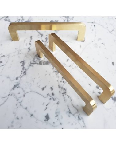 Tirador de mueble de latón cepillado ISA tirador de diseño trío colocado sobre una superficie con motivo