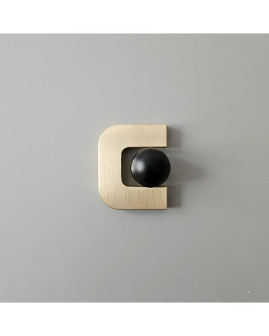 Tirador de mueble en oro pulido ISA XS tirador de diseño con una esfera negra colocada en el interior de la apertura