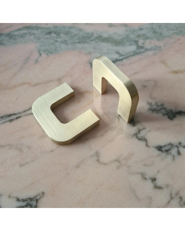 Tirador de mueble en oro pulido ISA XS tirador de diseño colocados de manera perpendicular sobre una superficie marmolada