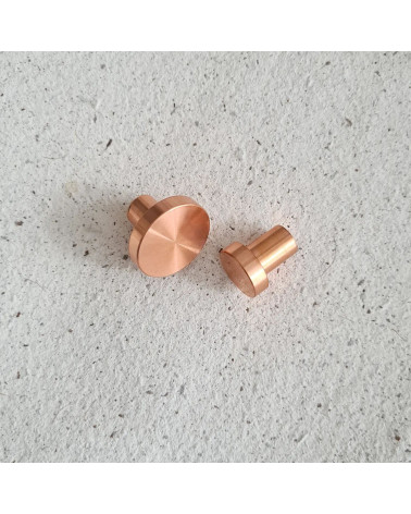 Botón de mueble en latón NENA tirador de diseño colocados uno al lado del otro sobre una superficie plana