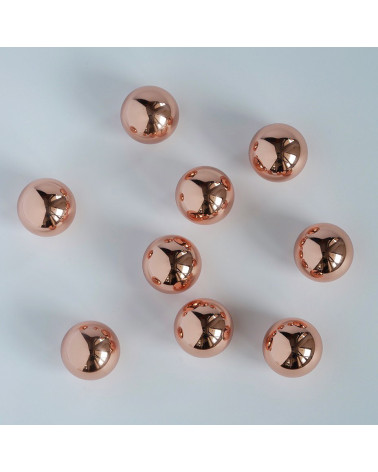 Tirador de mueble de cobre ODETE M tirador de diseño dispuestos de manera aleatoria sobre una superficie blanca con reflejos bri