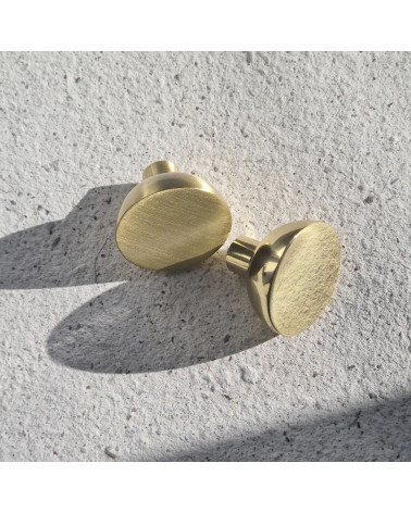 Tirador de mueble dorado pulido LUNA M tirador de diseño vista en zoom colocado sobre una placa texturizada