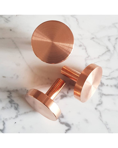 Tirador de mueble en latón NENA M diseño colocado sobre una superficie marmolada