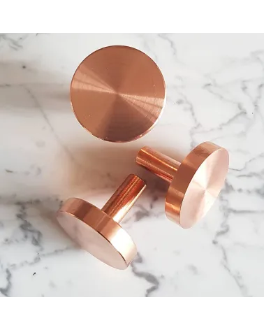 Tirador de mueble en latón NENA M diseño colocado sobre una superficie marmolada