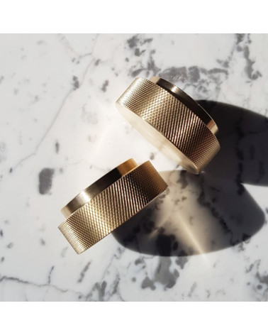 Tirador de mueble en oro mate TOVE diseño inclinado visto desde arriba sobre una superficie marmolada blanca con sombras