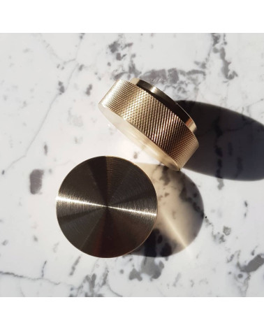 Tiradores de mueble en oro mate TOVE diseño vistos desde arriba ligeramente inclinados colocados sobre una superficie marmolada 