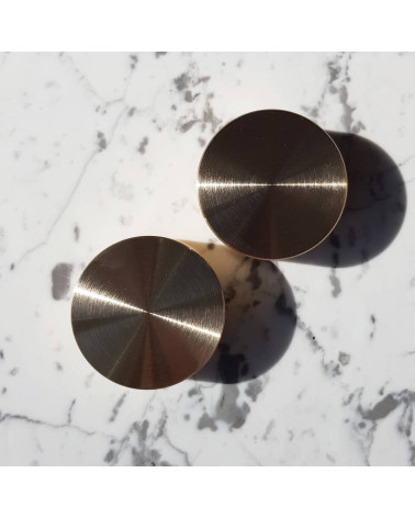 Tirador de mueble en oro mate TOVE diseño colocado sobre una superficie marmolada blanca
