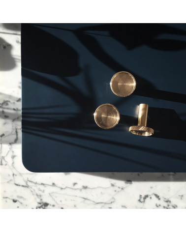 Tirador de mueble en latón VERA diseño colocado sobre una mesa negra