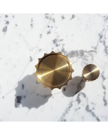 Botón de mueble en oro pulido LEXI tirador de diseño visto desde arriba alineado horizontalmente sobre fondo marmolado