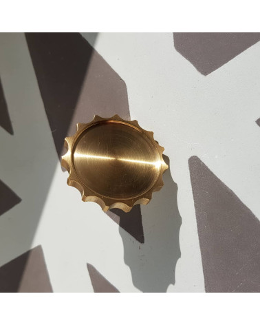 Botón de mueble en oro pulido LEXI tirador de diseño modelo grande vista frontal ligeramente inclinada colocado sobre fondo con 