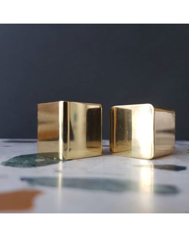 Botón de mueble en latón LANA S tirador de diseño vista de frente colocados sobre una superficie de mármol con toques de color