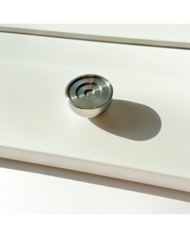 Tirador de mueble en acero inoxidable modelo 02 diseño colocado sobre una superficie iluminada proyectando una sombra