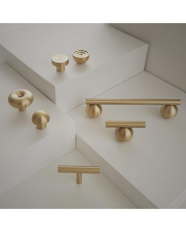 Tirador de mueble de latón modelo 04 diseño colocado sobre una superficie clara en escalera