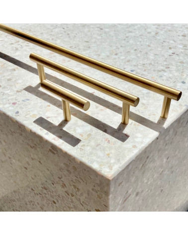 Tirador de mueble de latón T-Bar diseño vista lateral sobre una superficie de piedra con tiradores alineados al fondo