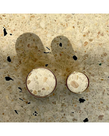 Tiradores de mueble en latón y Terrazzo de diseño vistos desde arriba alineados sobre una superficie de terrazzo