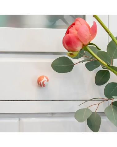 Botón de mueble de madera de haya rojo cereza, tirador de diseño montado en un mueble acompañado de una rosa colocada encima