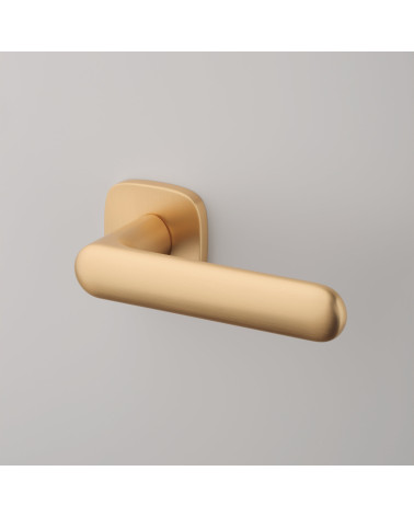 Maneta de puerta dorada mate OLEA diseño vista superior inclinada fijada sobre un fondo