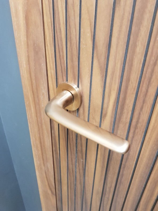 tirador de puerta dorado mate sobre una puerta de madera